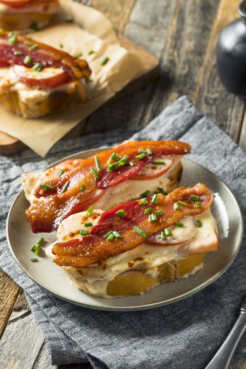 open faced louisville hot brown grilled cheese topped with tomato slices, bacon, chopped green chives