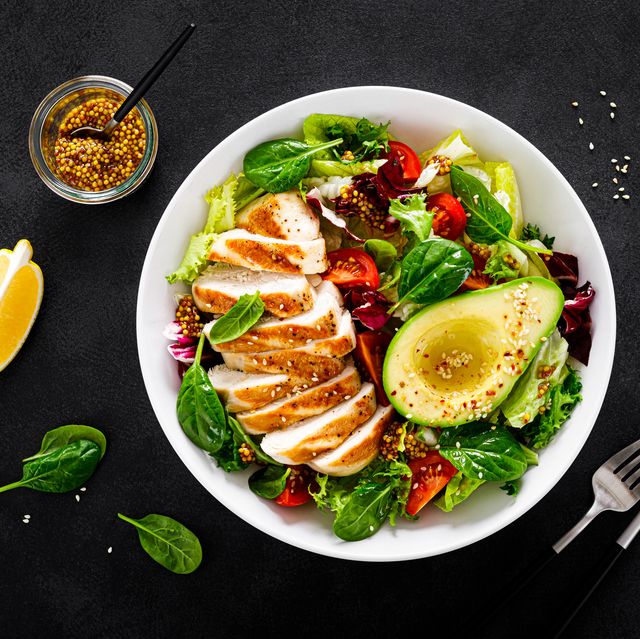 grilled chicken breast and fresh vegetable salad of tomato, avocado, lettuce and spinach. top view, flat lay