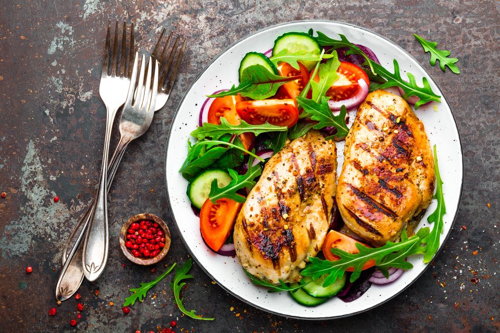 grilled chicken breast fried chicken fillet and fresh vegetable salad of tomatoes, cucumbers and arugula leaves chicken meat with salad healthy food flat lay top view dark background