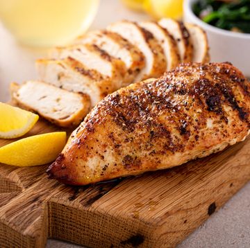 grilled chicken breast whole and sliced on a cutting board with lemon