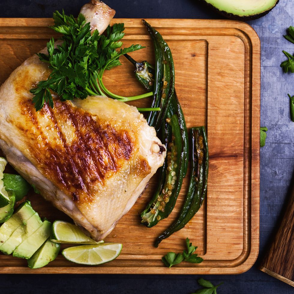 grilled chicken leg and green vegetables on cutting board