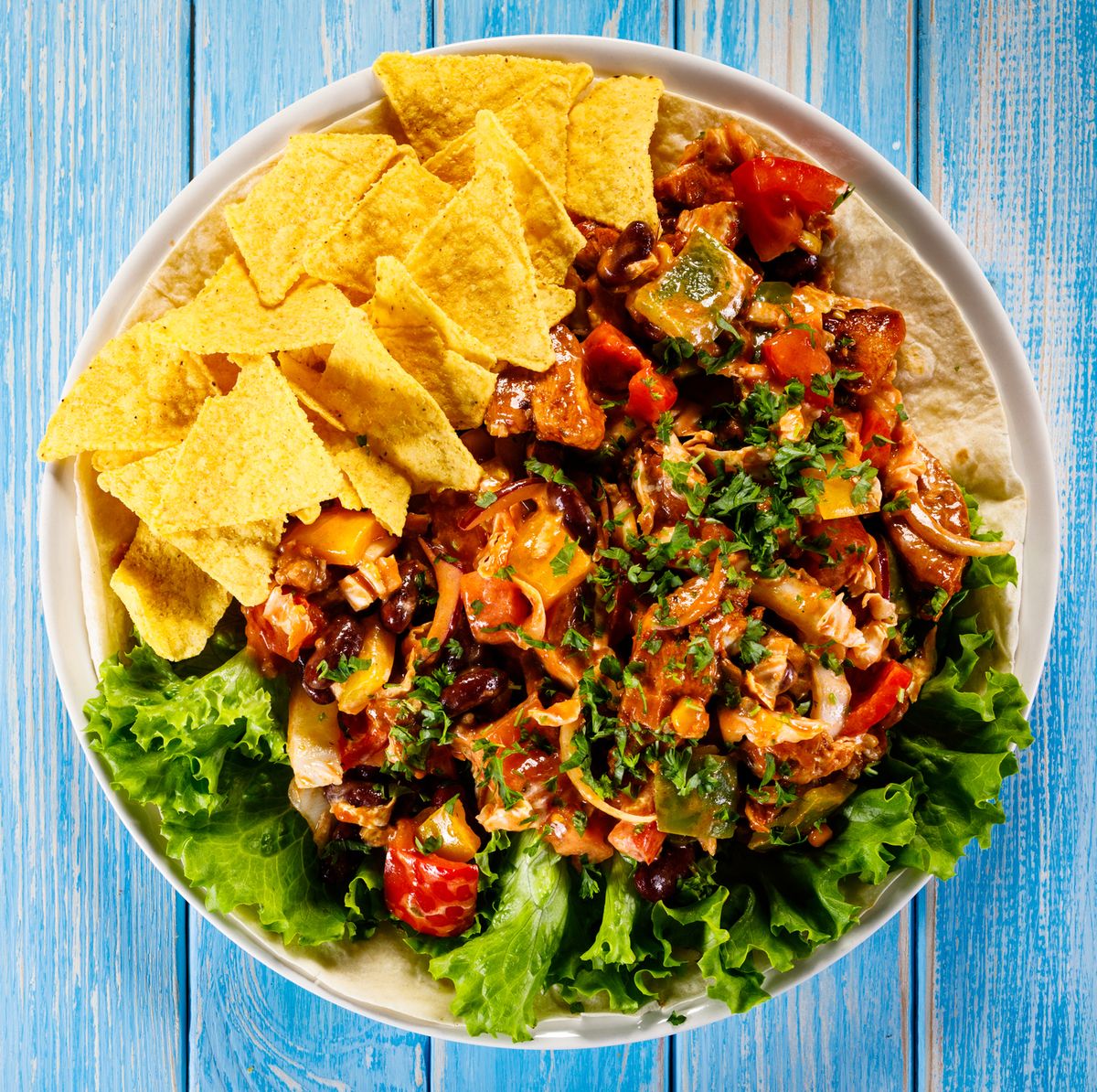 grilled chicken meat, nachos and vegetables on wooden background
