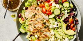 salad topped with sliced grilled chicken, cucumbers, cherry tomatoes, olives, and feta