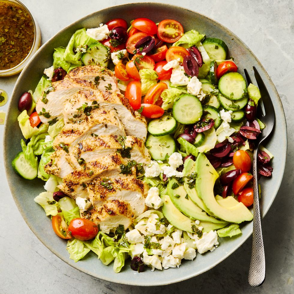 salad topped with sliced grilled chicken, cucumbers, cherry tomatoes, olives, and feta