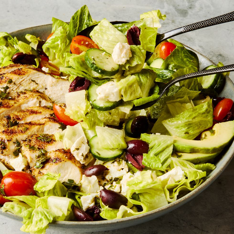 salad topped with sliced grilled chicken, cucumbers, cherry tomatoes, olives, and feta