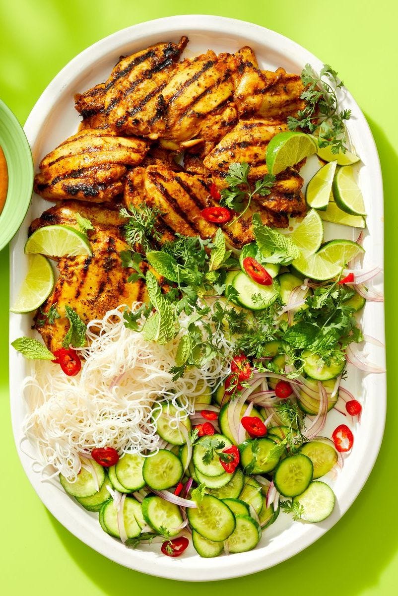 a platter with grilled chicken, sliced cucumbers and noodles