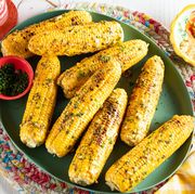 grilled corn on the cob on green platter with chives and butter