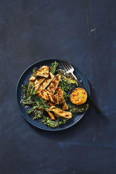 grilled lemony chicken and kale on a dark blue plate