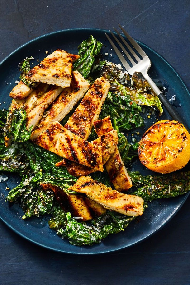 grilled lemony chicken and kale on a deep blue plate with fork