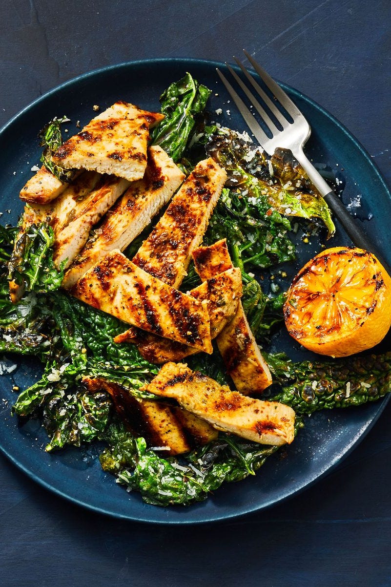 grilled lemony chicken and kale on a deep blue plate with fork