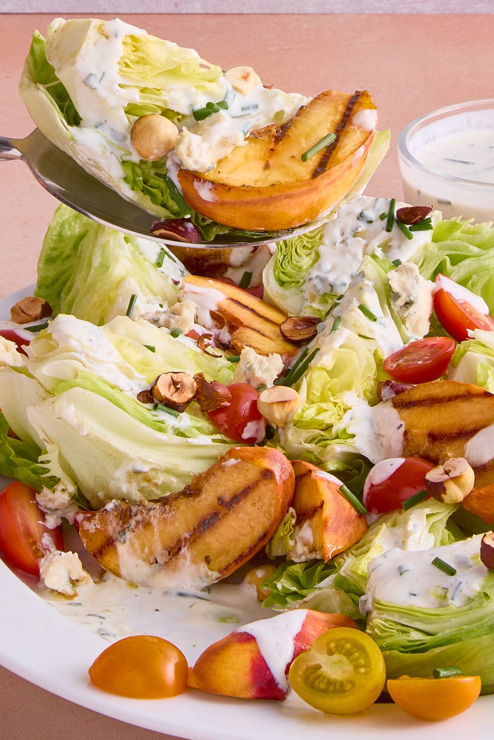 lettuce topped with grilled peach slices, tomatoes, toasted hazelnuts and creamy buttermilk dressing