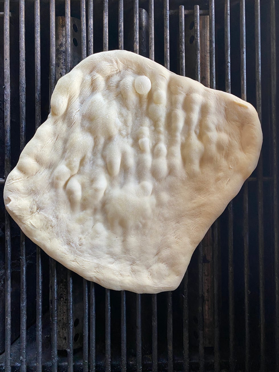 pizza dough on grill with bubbles