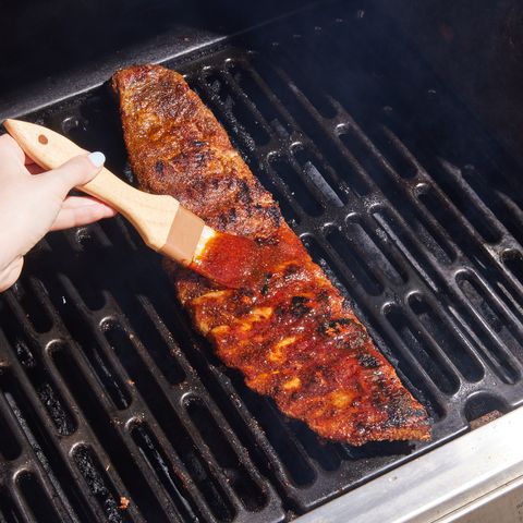 grilled ribs getting slathered with sauce