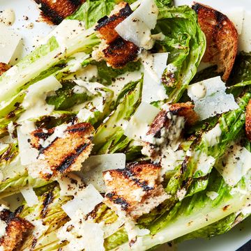 grilled romaine lettuce wedge topped with caesar dressing and croutons on a white platter