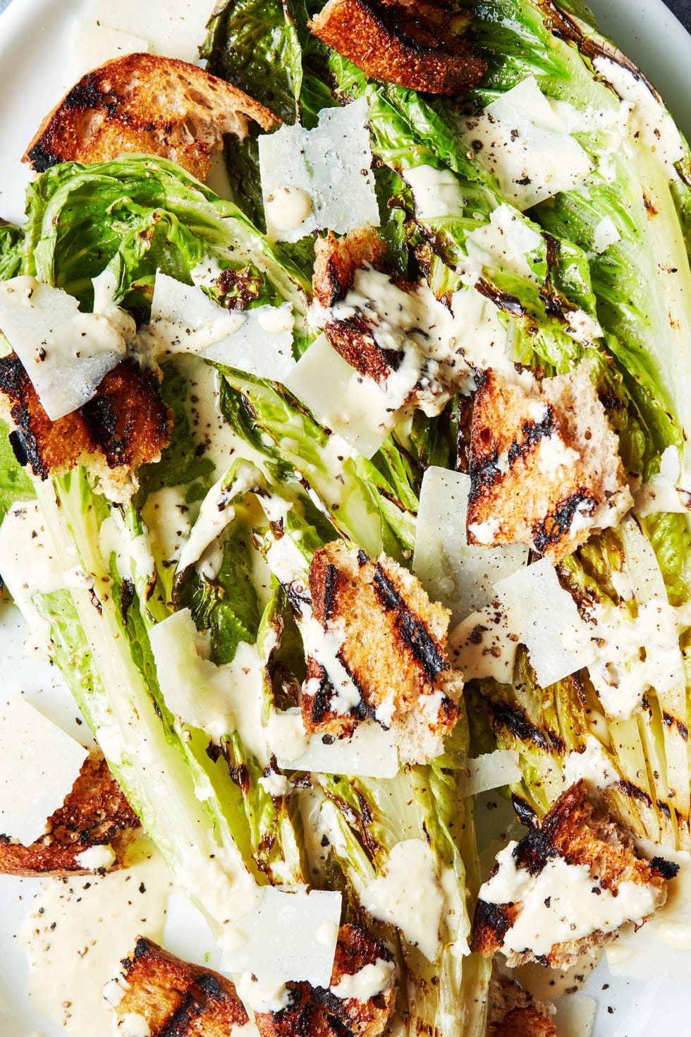 Grilled Romaine Lettuce Wedge grilled romaine lettuce wedge topped with caesar dressing and croutons on a white platter