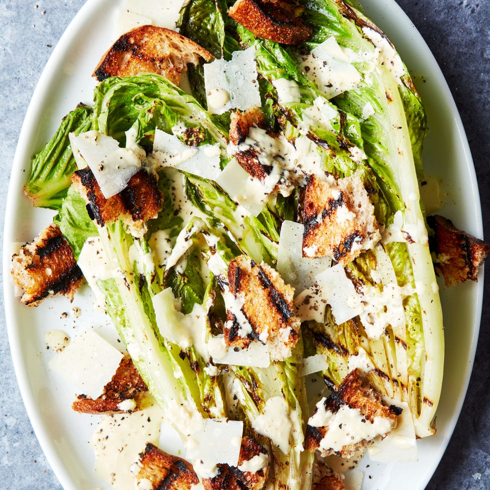 grilled romaine lettuce wedge topped with caesar dressing and croutons on a white platter