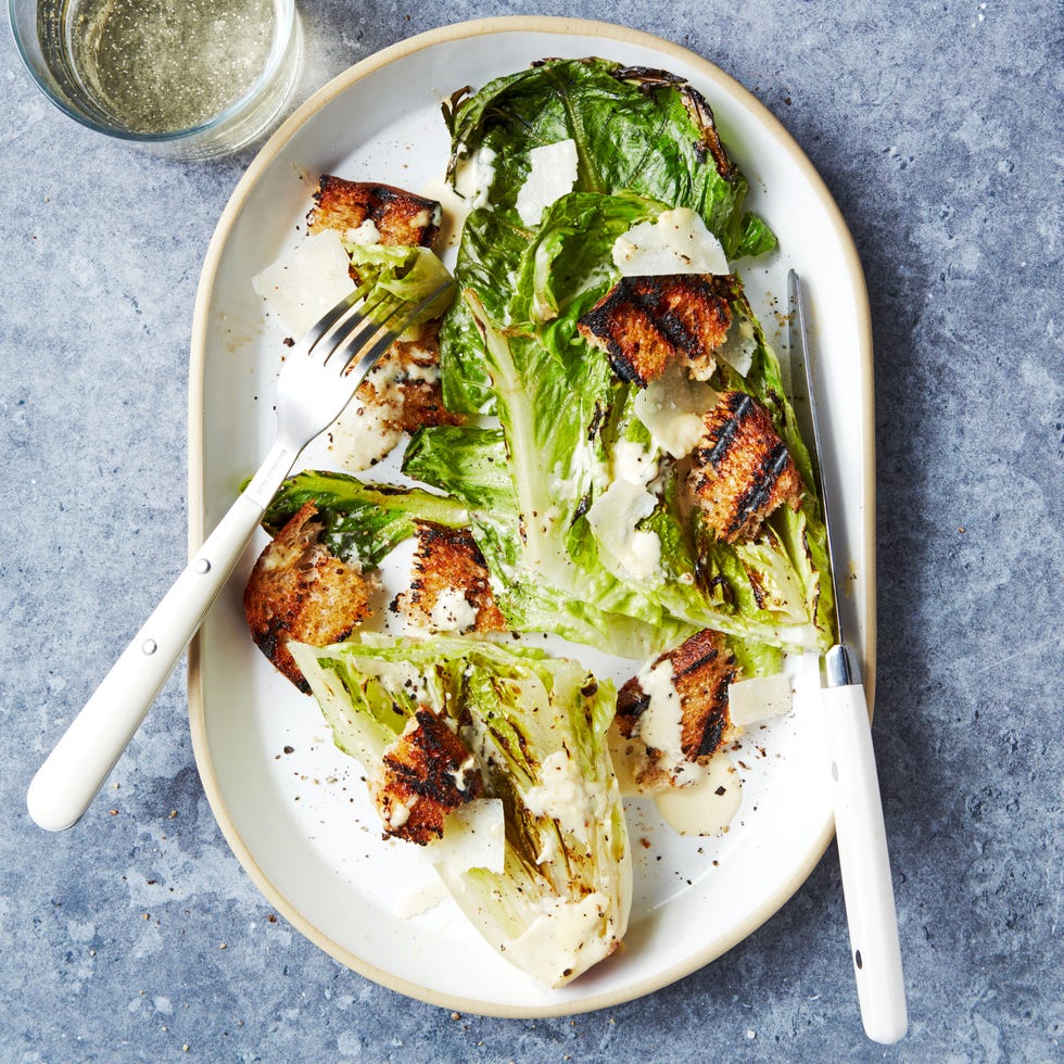 grilled romaine lettuce wedge topped with caesar dressing and croutons on a white platter