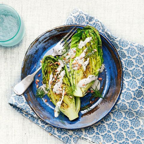 grilled romaine lettuce with creamy feta dressing on a blue plate