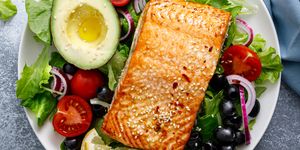 grilled salmon fish fillet and fresh vegetable salad with tomato, red onion, black olives and avocado