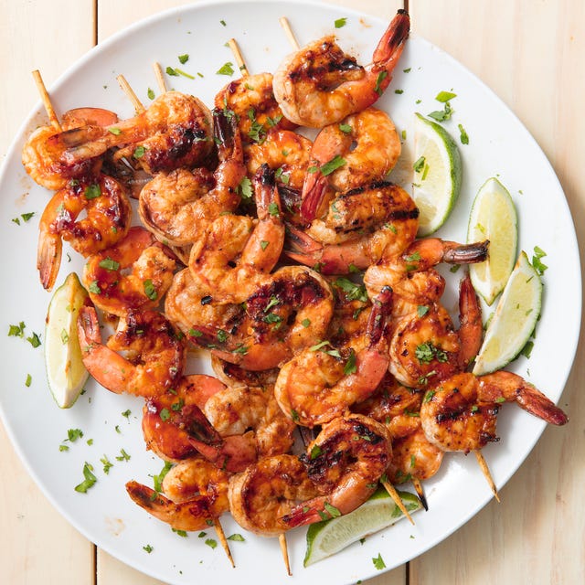 grilled shrimp skewers served with lime wedges and garnished with parsley