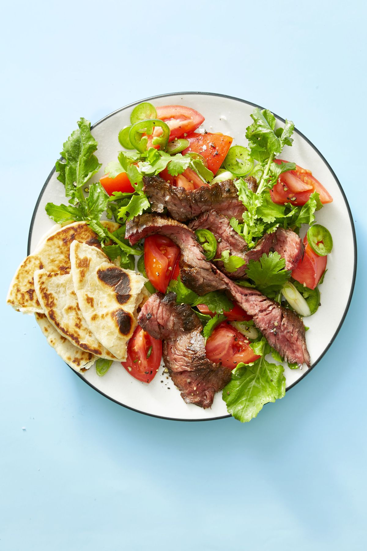grilled steak tortilla salad on a white plate on a blue background