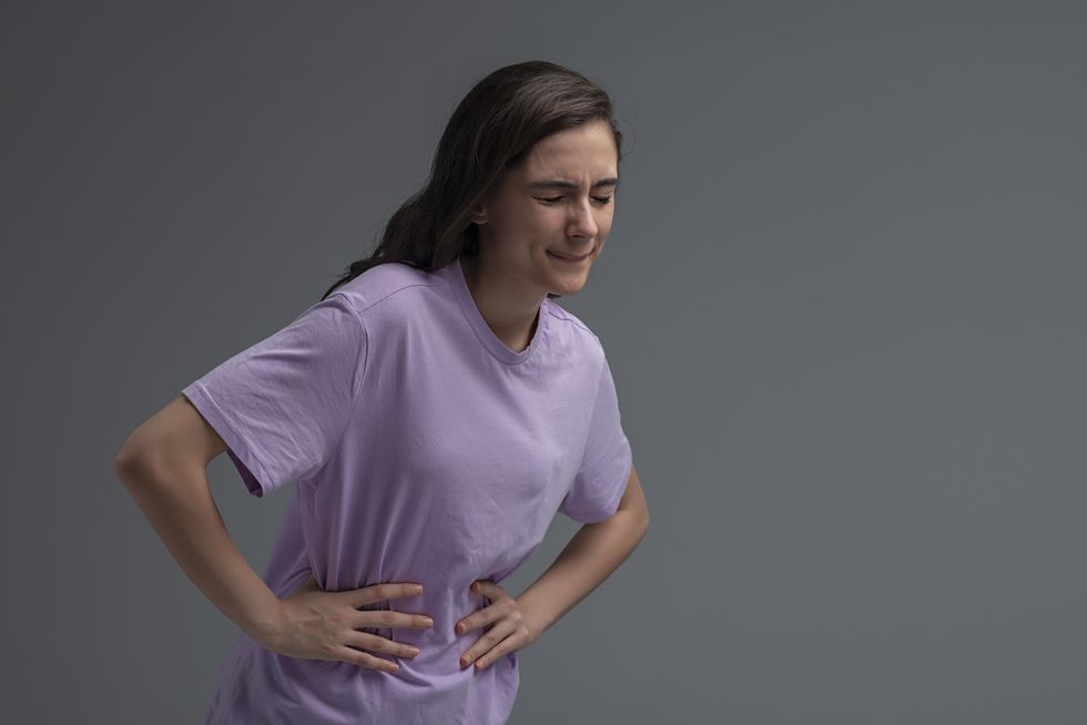 grimacing young woman suffering from stomach ache