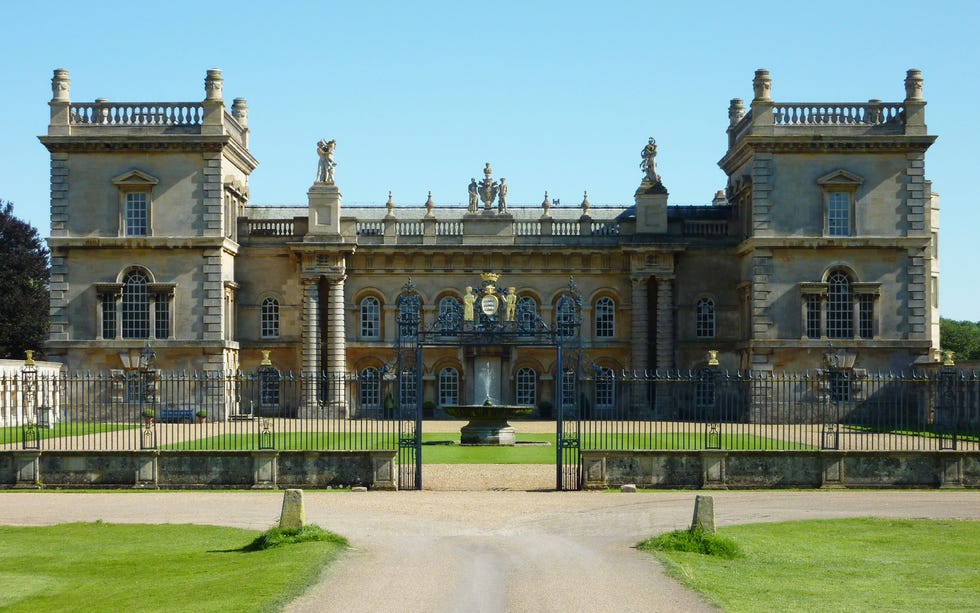 a large stone building with a fence around it with grimsthorpe castle in the background