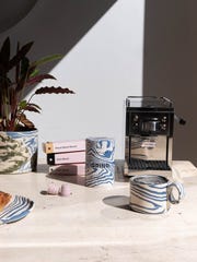 a marbled coffee jar and mug on a table next to a coffee machine and pods