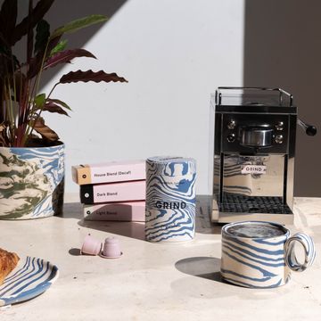 a marbled coffee jar and mug on a table next to a coffee machine and pods