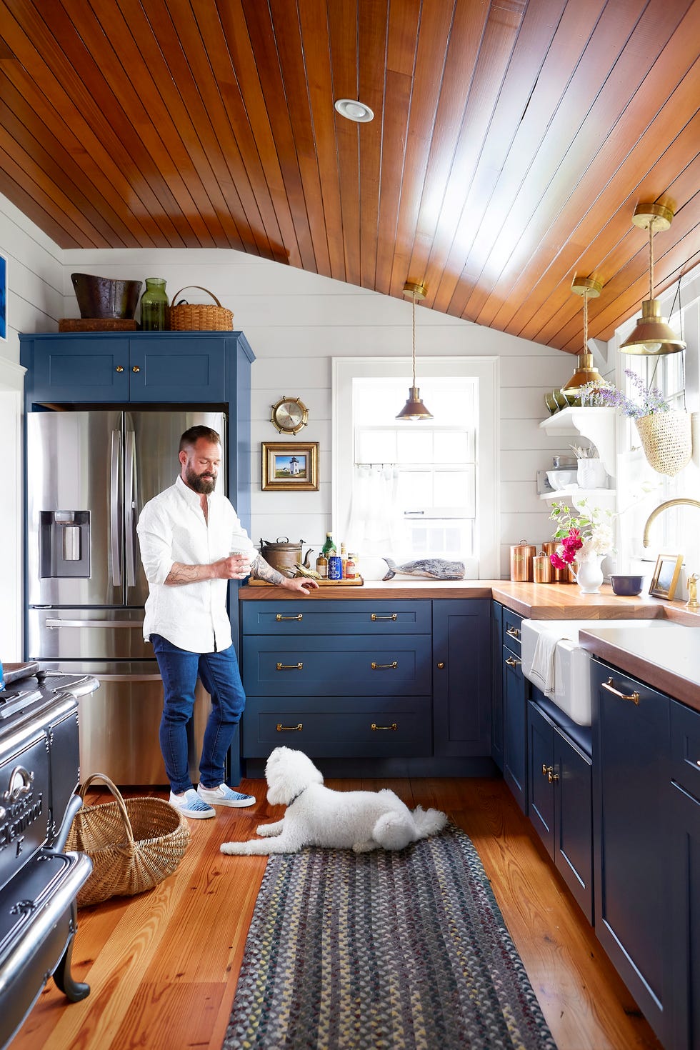 nautical kitchen with navy cabinetry and brass lighting