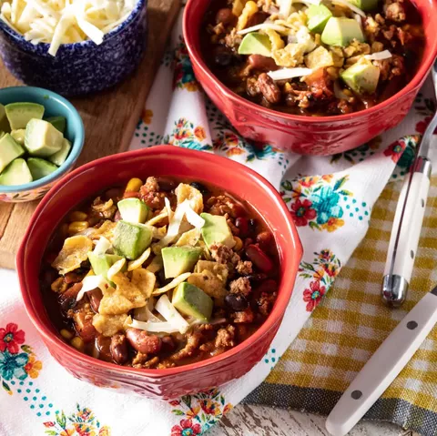 slow cooker turkey chili in red bowl with avocado and chips