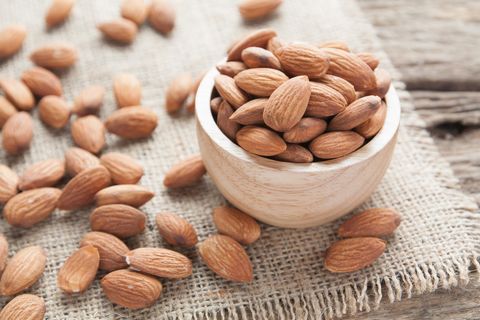 group of almonds  from wood bowl on wood background