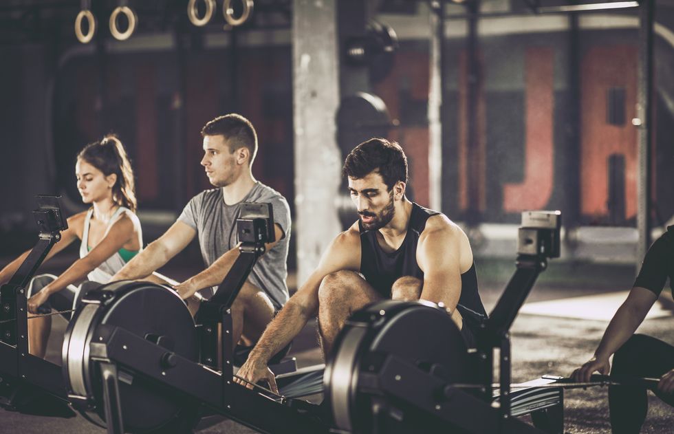Group of athletes exercising on rowing machines in a gym.