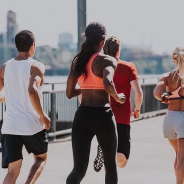 group of athletes jog on waterfront running path in city