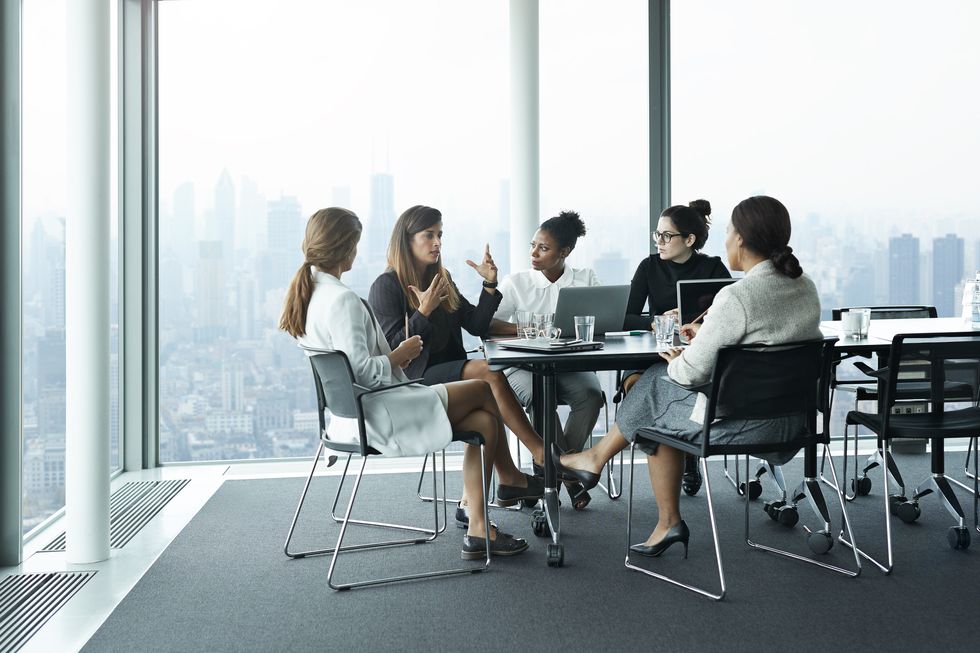 group of businesswomen having meeting in boardroom with stunning skyline view