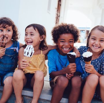group of cheerful multiethnic children eating icecream in summer