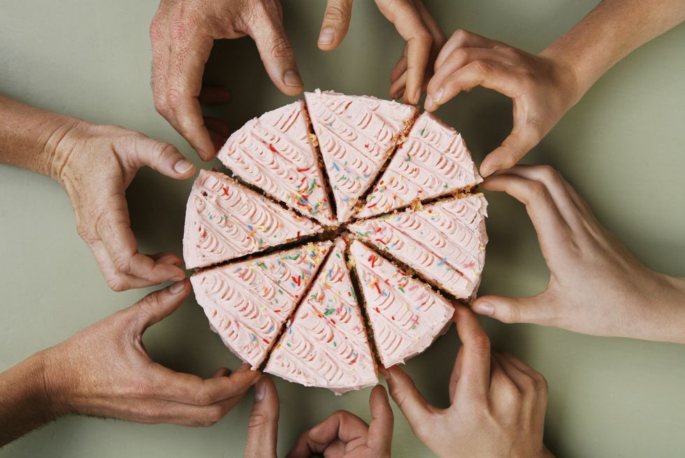 group of eight people reaching for slice of cake, close up, overhead view