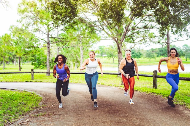 un grupo de mujeres esprintan en un parque durante una carrera