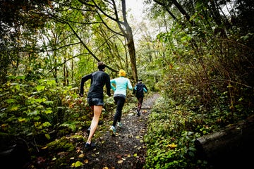 group of female friends running up forest trail