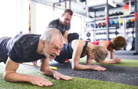 group of fit seniors with personal trainer in gym