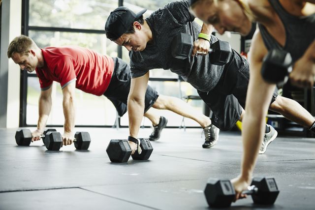 group of friends doing pushups with dumbbells