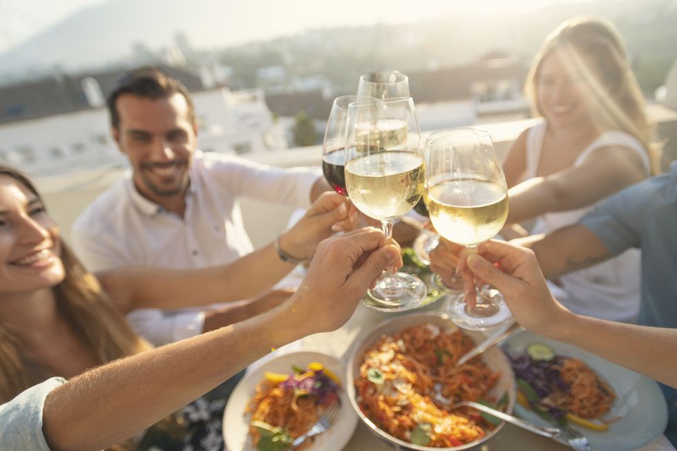 group of friends having a meal outdoors they are celebrating with a toast using wine