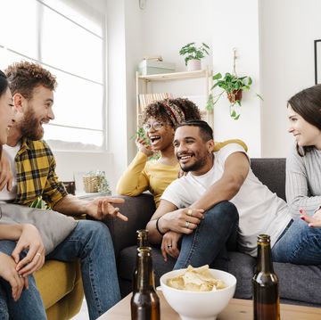 a group of friends having fun at home chatting, eating snacks and drinking beer