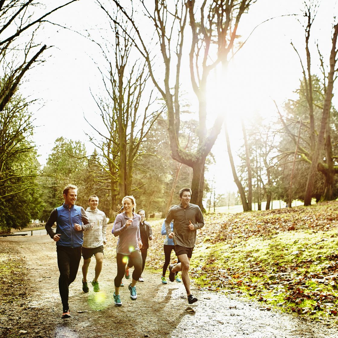 group of friends running together on trail in park