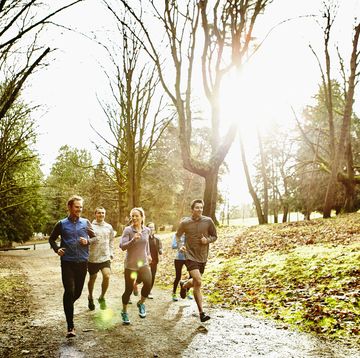 group of friends running together on trail in park