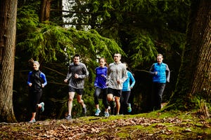 Group of friends running together on trail in park