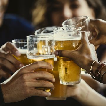 group of friends toasting beer glasses at table in bar