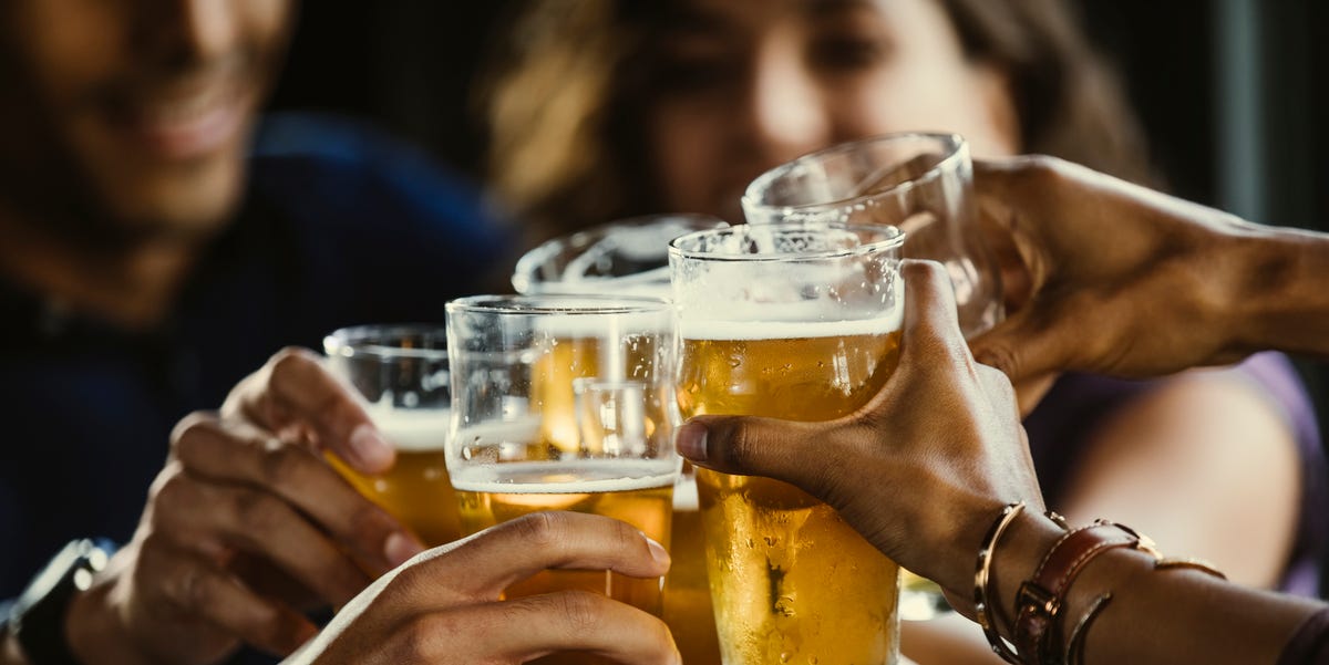 group of friends toasting beer glasses at table in bar