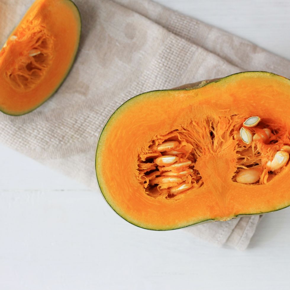 group of halves and whole pumpkin on a light wooden background pumpkin is not cleared of seeds