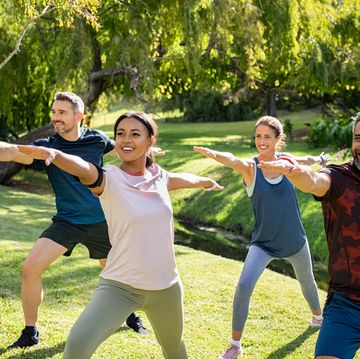 group of mature men and women stretching at park after workout